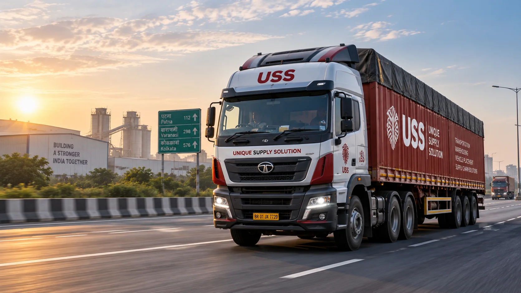 A USS-liveried Tata articulated truck travelling an Indian national highway at sunrise, with an industrial plant and highway signage to Patna, Varanasi and Kolkata behind it